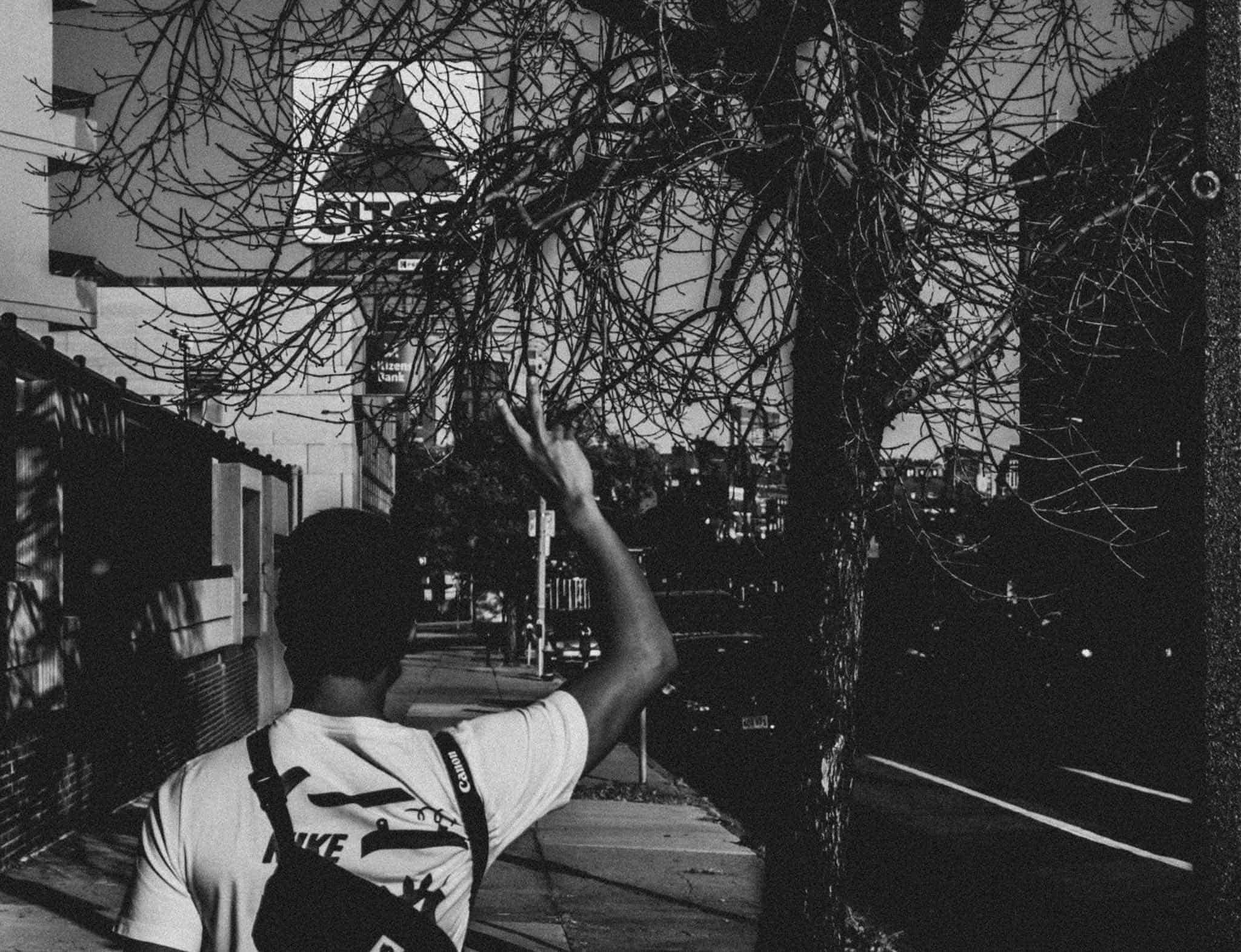 Dakila putting up a peace sign walking towards the Citgo sign