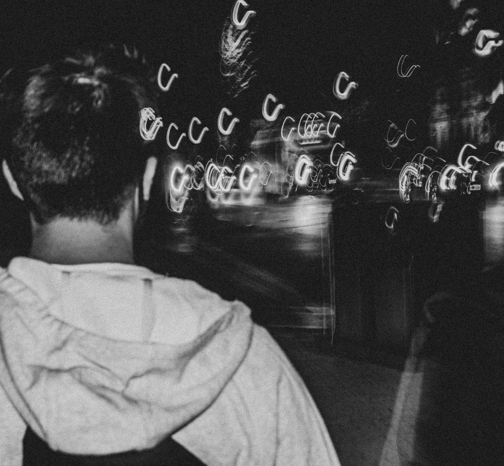 Dakila walking past blurry car headlights in black and white