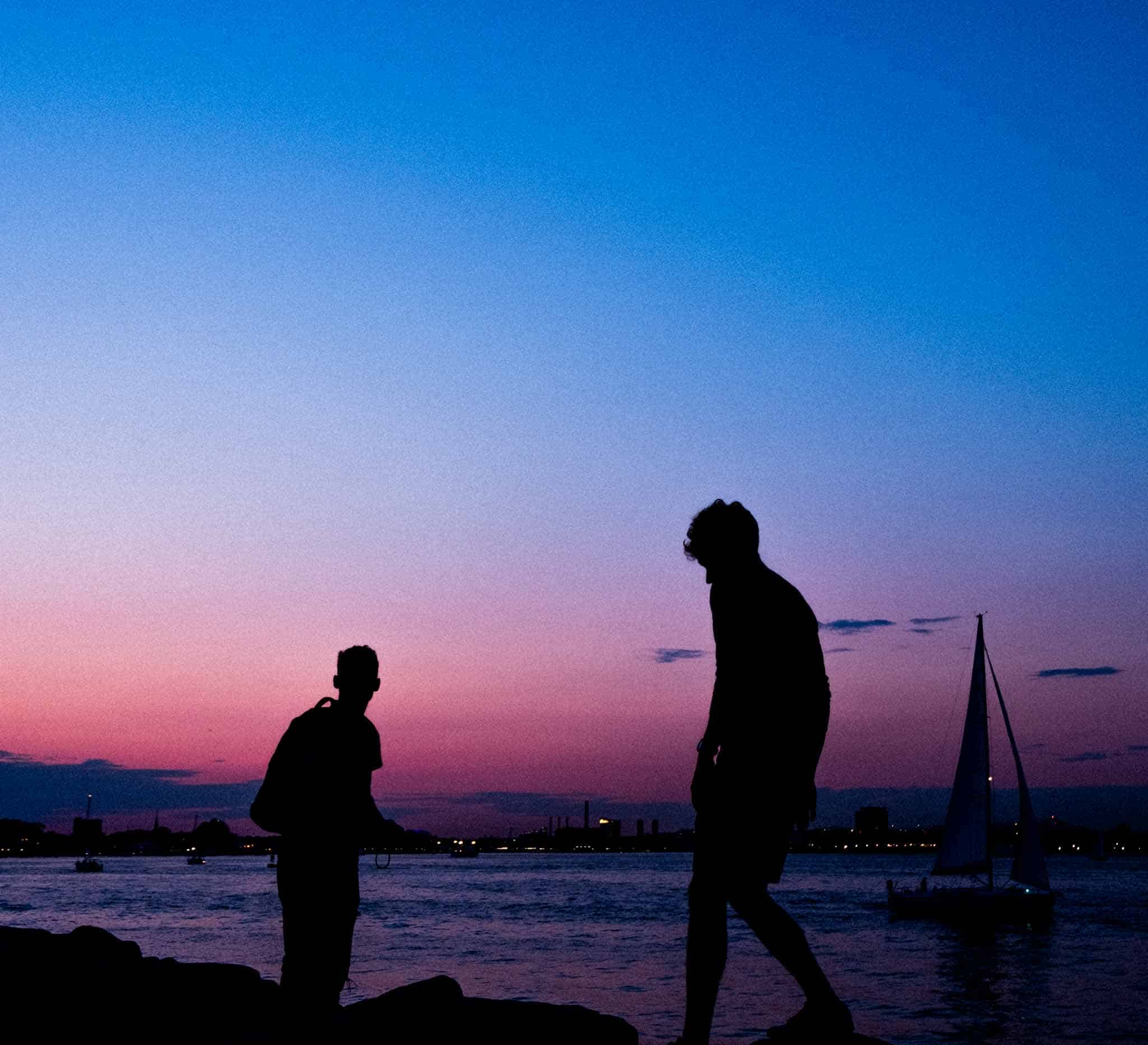 Gabe and Kabir moving on the rocks by the water at sunset