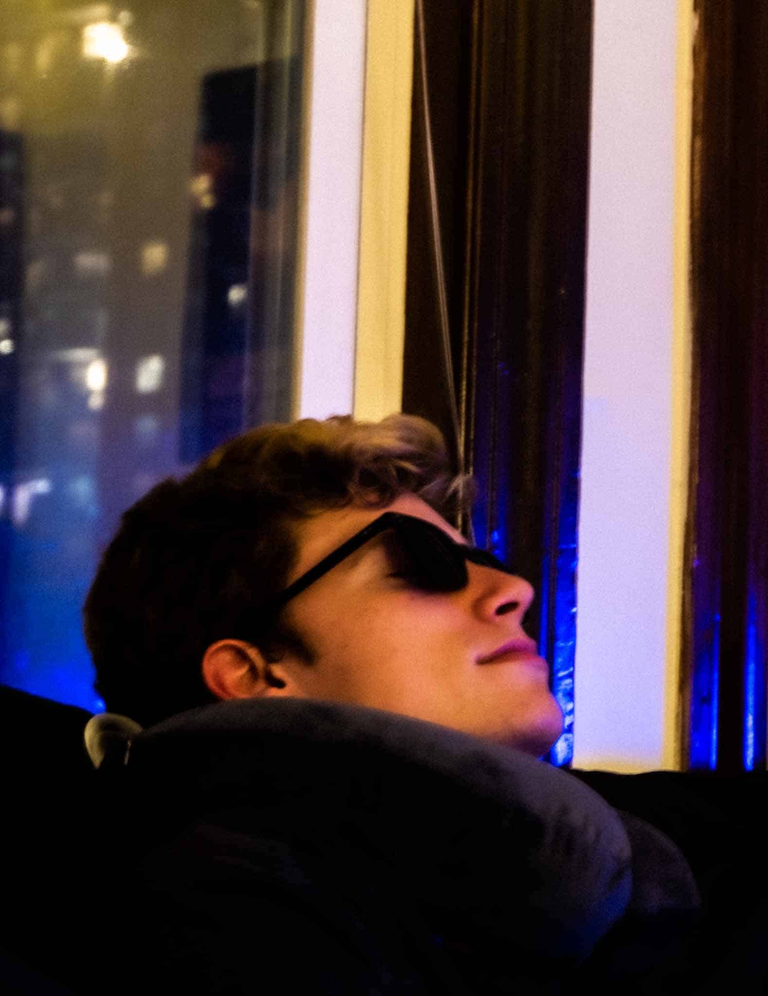 Gabe resting with a neck pillow and shades indoors