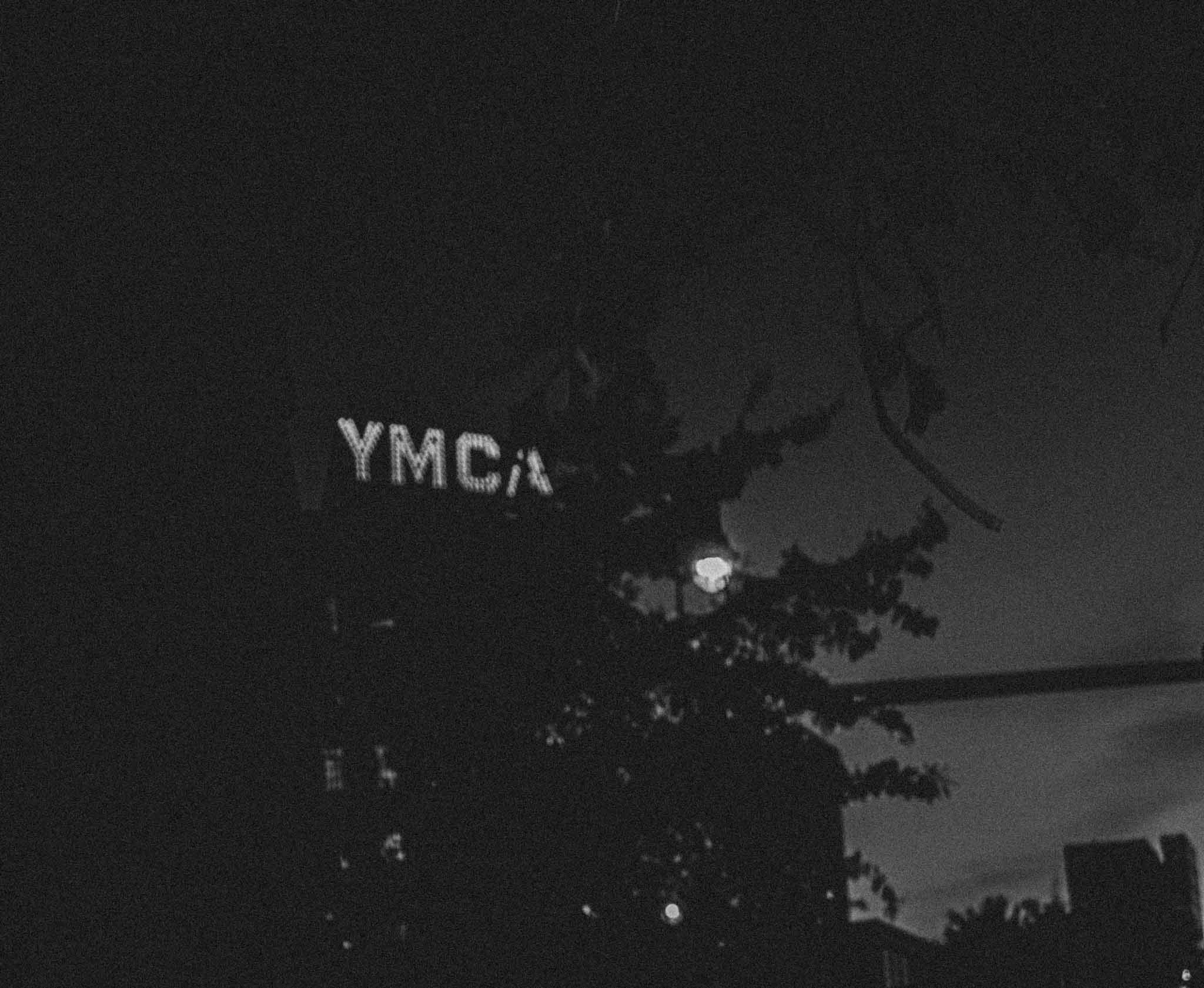 YMCA sign behind tree branches in black and white